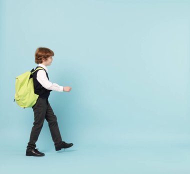 Açık mavi arka planda sırt çantası olan sevimli okul çocuğu, mesaj için yer var.