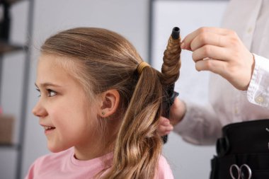 Güzel kız kuaförde saç buklesi yaptırıyor.