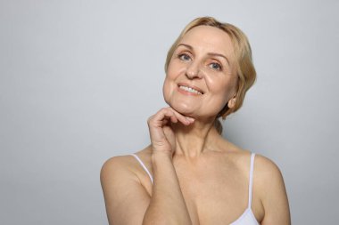 Gri arka planda gülümseyen orta yaşlı kadın. Metin için boşluk