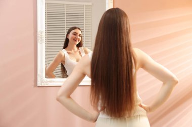 Güzel bir kadın aynada kendine bakıyor.