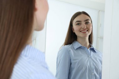 Güzel bir kadın aynada kendine bakıyor.