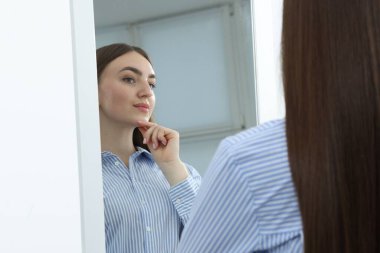 Güzel bir kadın aynada kendine bakıyor.