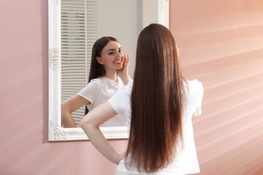 Güzel bir kadın aynada kendine bakıyor.