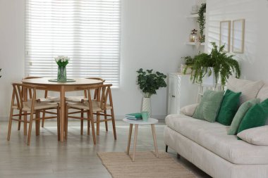 Rahat bir kanepe, masa, sandalyeler ve yeşil ev bitkileri. İç tasarım