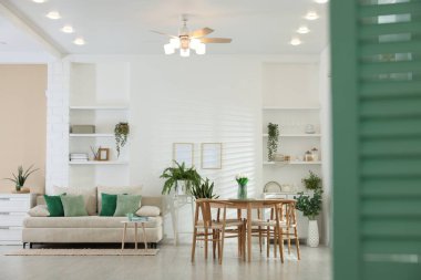 Rahat bir kanepe, masa, sandalyeler ve yeşil ev bitkileri. İç tasarım