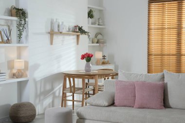 Odada rahat bir kanepe ve sandalyeli şık bir yemek masası. İç tasarım