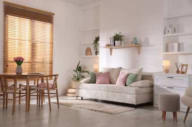 Odada rahat bir kanepe ve sandalyeli şık bir yemek masası. İç tasarım