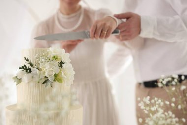 Evli çift içeride bıçakla lezzetli bir düğün pastası kesiyor.