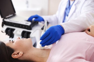 Sonograf klinikte kadının tiroid bezini ultrason taraması yapıyor.