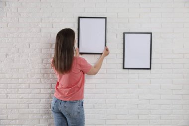 Beyaz tuğla duvara boş çerçeveler asan kadın, arka plan