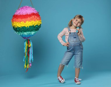 Parlak pinyatası olan ve açık mavi arka planı olan tatlı bir kız.