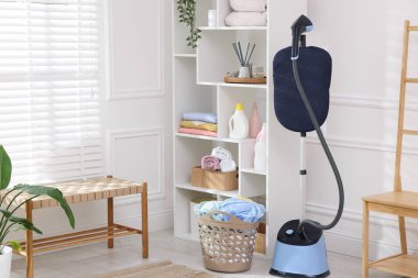 Kapalı alanda temiz çamaşırları olan modern, dik bir buharlı sepet.