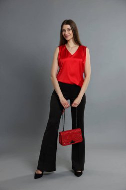 Gri arka planda şık giyinmiş güzel bir kadın.