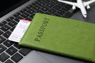 Pasaport, uçuş bileti ve uçak modeli bilgisayarda, yakın plan.