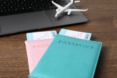 Pasaportlar, uçuş biletleri, uçak modeli ve laptop ahşap masada, yakın plan.