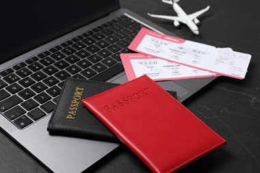 Pasaportlar, uçuş biletleri, uçak modeli ve laptop siyah masada, yakın plan.