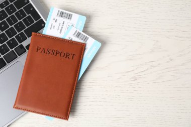 Pasaport, uçuş biletleri ve dizüstü bilgisayar beyaz ahşap masa, üst manzara. Metin için boşluk