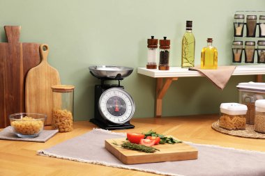 Kitchen scale, products and cooking utensils on wooden table