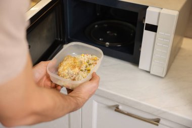 Yemek kabını mikrodalgaya koyan adam, yakın plan.