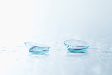 Kontakt lensler ve su damlaları beyaz ayna yüzeyine düşer. Yakın plan.