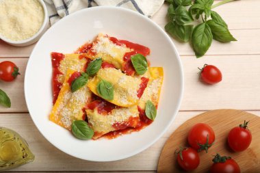 Domates soslu nefis ravioli, parmesan peyniri ve fesleğen beyaz ahşap masada, düz yatıyordu.