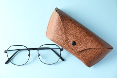 Açık mavi arka planda şık gözlüklü çanta, düz uzanma