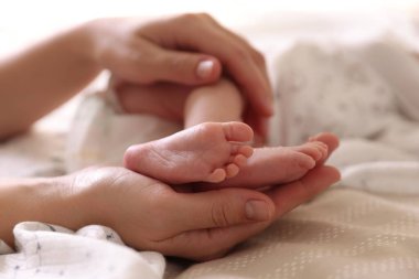 Anne, küçük bebeği evde, yatağında, yakın plan.