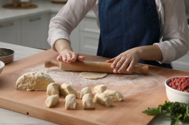 Khinkali yapıyorum. Mutfaktaki masada merdane şekilli hamuru olan kadın, yakın plan.