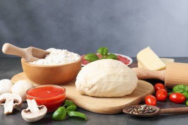 Pizza yapıyorum. Gri desenli masadaki farklı malzemeler