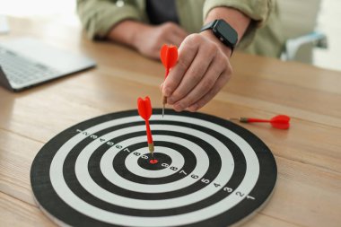 Dart oklu bir adam içeride çalışırken dart tahtasına nişan alıyor, yakın plan.