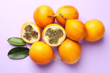 Olgun sarı çarkıfelek meyveleri ve yaprakları leylak arka planda, düz yatıyordu.