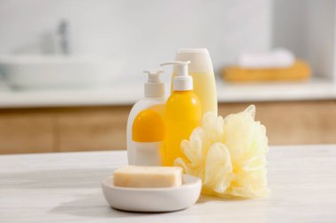 Banyodaki beyaz ahşap masada farklı banyo ürünleri.