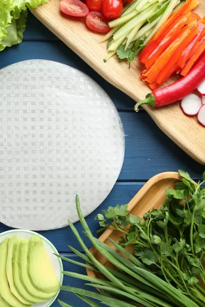 Pirinç kağıt çarşaflar ve mavi ahşap masa üzerindeki farklı malzemeler.