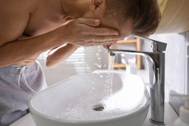 Tuvalette yüzünü yıkayan bir adam.