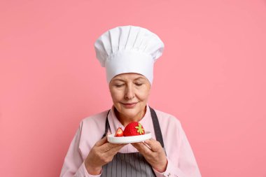 Pembe arka planda tatlı yapan profesyonel bir şekerci.