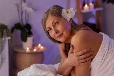 Son sınıf öğrencisi kadın masaj salonundaki masaj koltuğunda dinleniyor, mesaj atmak için yer var.