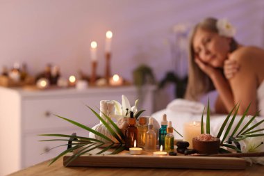 Üst düzey kadın masaj koltuğunda dinleniyor, farklı spa ürünlerine odaklanıyor.