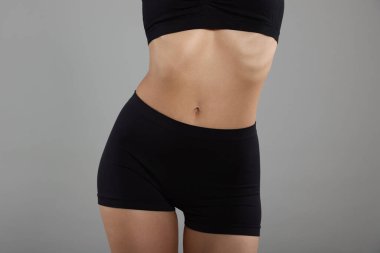 Gri arka planda mükemmel ince vücutlu kadın, yakın plan.