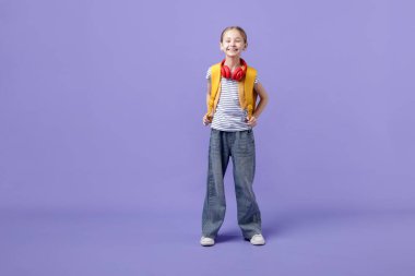 Mor arka planda sırt çantası ve kulaklığı olan şık bir kız öğrenci.