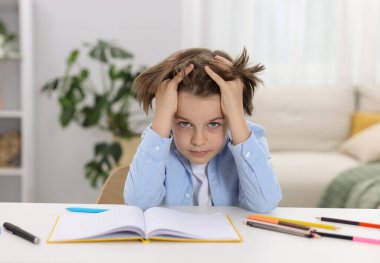 Evde, masada ödev yapmaktan yorgun düşmüş küçük çocuk.