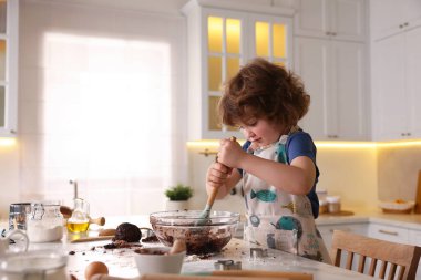 Yemek tarifi. Küçük çocuk mutfaktaki masada kurabiye için para kazanıyor. Metin için boşluk