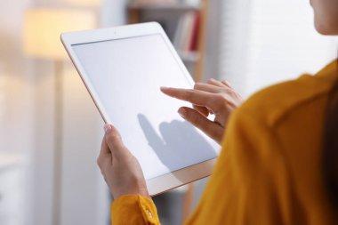 Modern tabletli kadın kapalı mekanda, yakından bakıyor.