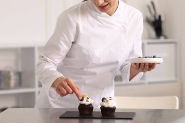 Şekerci mutfakta yabanmersinli kek dekore ediyor.