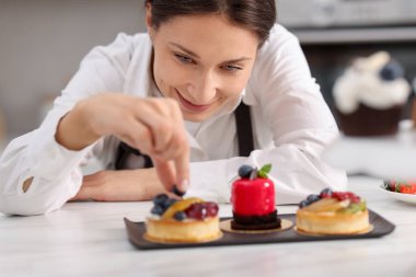 Sofrada yaban mersinli tart süsleyen şekerci.