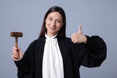 Gri arkaplanda baş parmak gösteren çekiçli yargıç