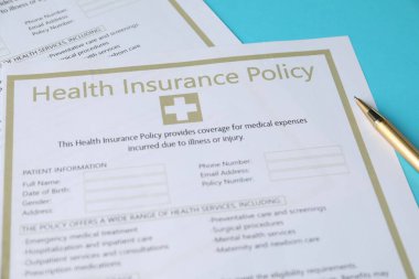 Sağlık sigortası formları ve açık mavi arka planda bir kalem.