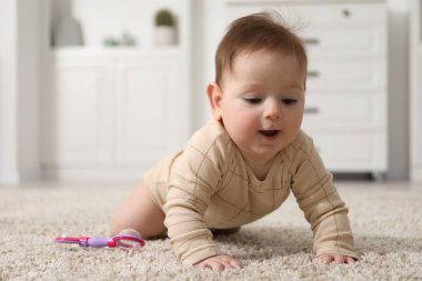 Evde yerde çıngıraklı oyuncağı olan şirin bir bebek.