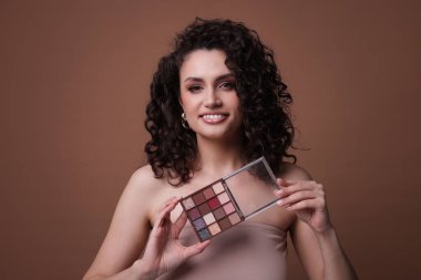 Kahverengi arka planda göz falı olan gülümseyen kadın.