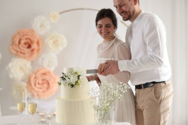 Evli çift evde bıçakla düğün pastası kesiyor, seçici bir odak noktası var.