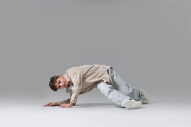 Açık gri arka planda dans eden şık elbiseli bir çocuk.